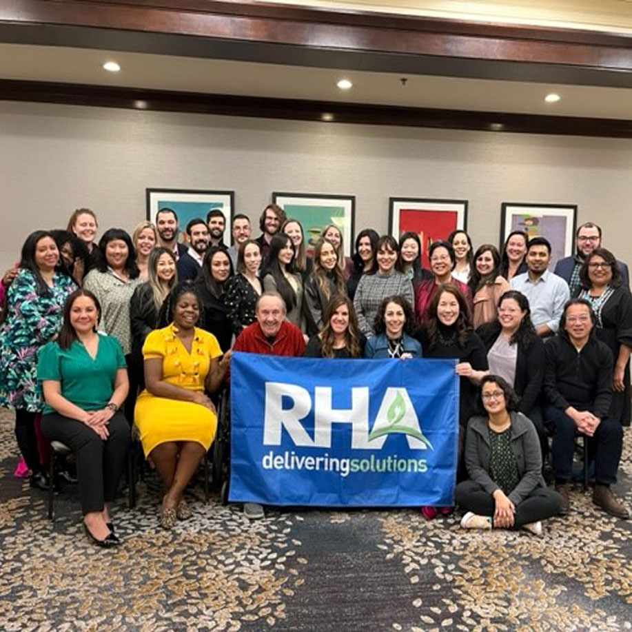A Group Of People Smiling For The Camera, Holding The RHA Flag